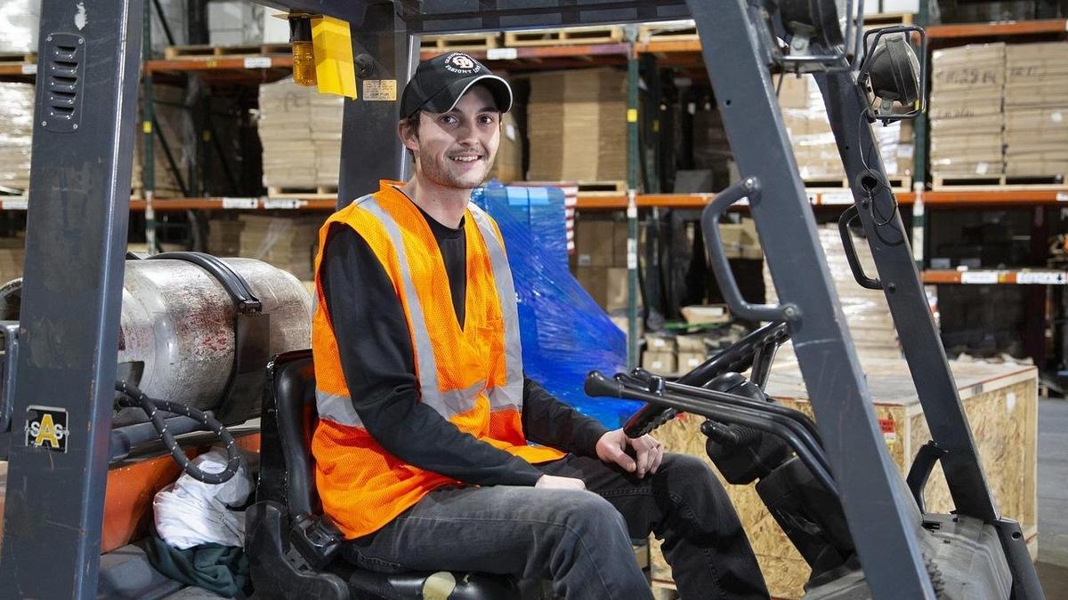 倉庫で作業用フォークリフトを運転する男性
