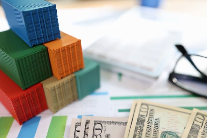 Cargo containers with dollar banknotes and glasses on financial document.
